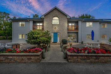 Symmetrical two-story building at sunset with colorful flower beds.