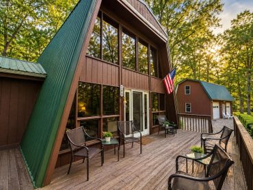 A-frame cabin with a wooden deck and outdoor seating.