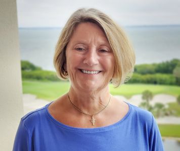 Smiling woman in blue top with ocean view in background. lead patient advocate