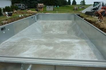 Empty rectangular metal and concrete pool structure under construction outdoors.