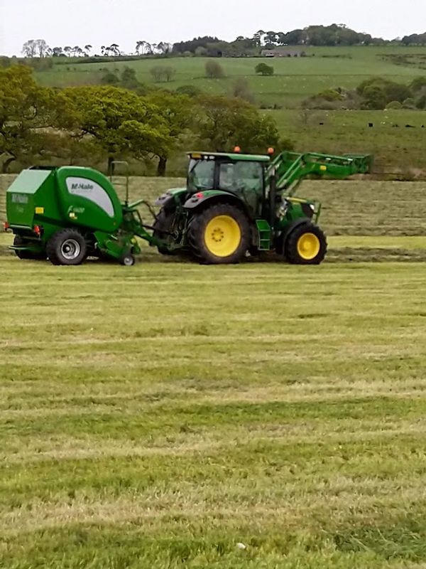 tractor and baler baling grass with winter cattle feed