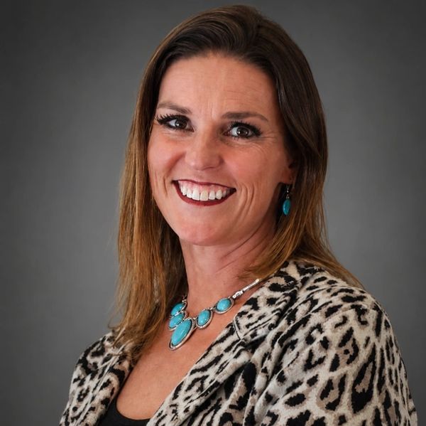 Smiling woman wearing leopard print and turquoise jewelry.