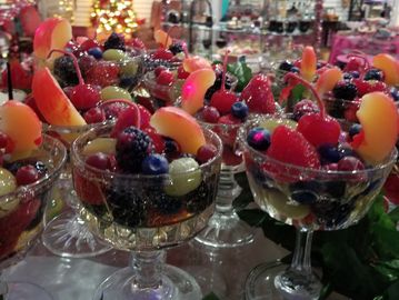 Elegant glass cups filled with assorted fresh fruits at a festive event.