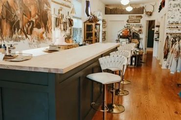 A long wood bar with stools in front of it and a western mural behind it