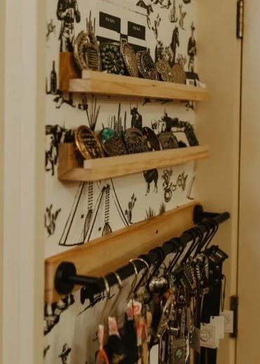 Belt buckles sitting against a wall with belts hanging on a bar below it.