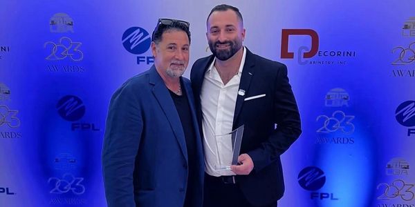 Two men posing at an awards event with one holding a trophy.