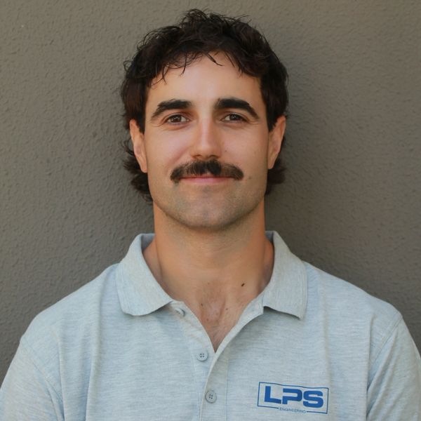 Man with a mustache wearing a light grey LPS polo shirt against a grey background.