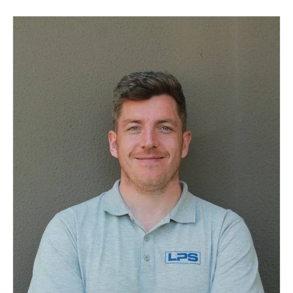 Smiling man in light grey LPS Engineering polo shirt with arms crossed.