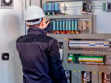 Técnico eléctrico revisando un panel de control.