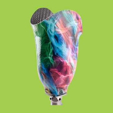 Colorful prosthetic leg cover with swirling smoke design on green background.