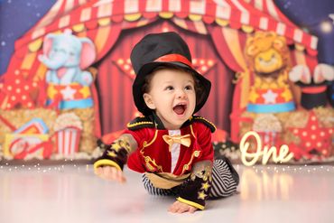 A joyful toddler in a circus ringmaster costume celebrates their first birthday.