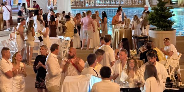 People socialize at a lively poolside party during the evening.