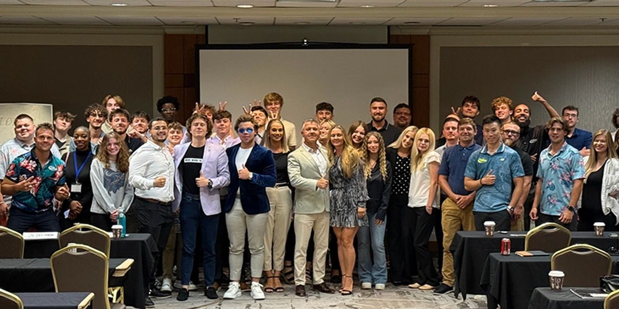 Large group posing together in a conference room with a projector screen behind.