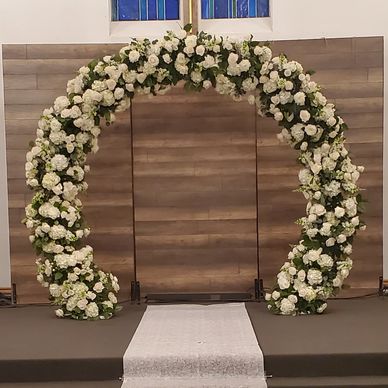 White floral arch with greenery.