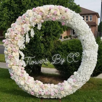 Large floral wreath made of white and pink flowers outdoors.