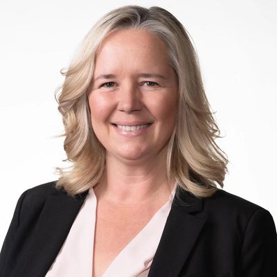 Professional woman with blonde hair smiling in business attire.