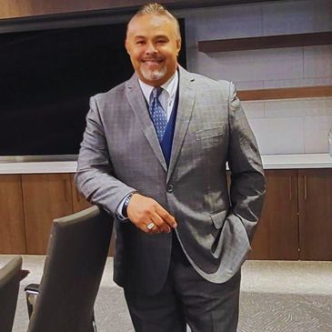 Man in a gray suit smiling.