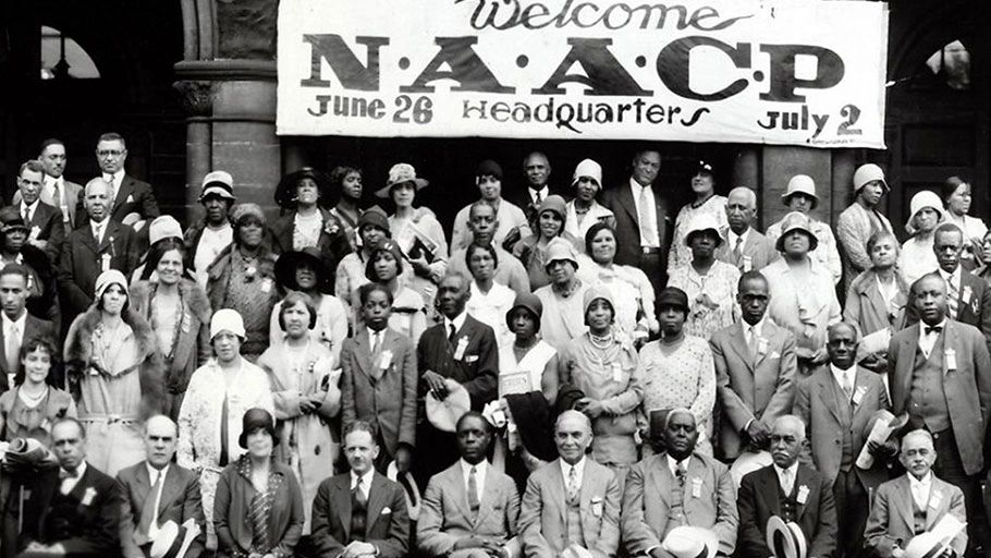 Black and white group photo at NAACP headquarters with a welcoming banner.