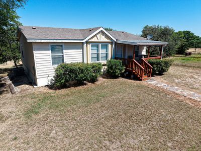 Small house with a front porch and bushes.