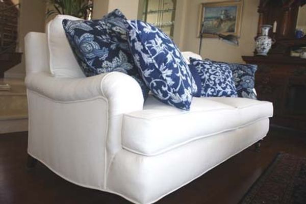 A white sofa with blue patterned cushions in a classic living room setting.