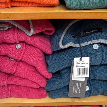 Stacked red and blue folded sweaters on a shelf.