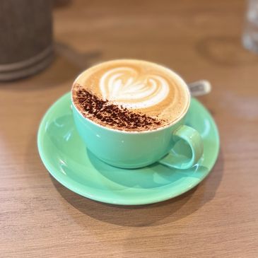 Latte coffee in a turquoise cup with foam art.