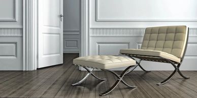 Modern white chair and ottoman in a minimalist room with an open door.