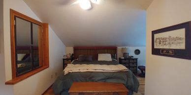 Cozy bedroom with a wooden bed and slanted ceiling.