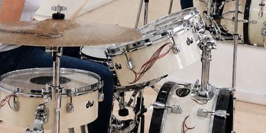Close-up of a white drum set with a rider cymbal.