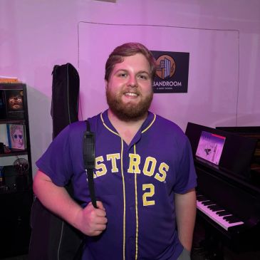 Man smiling, wearing Astros jersey, holding a bag.