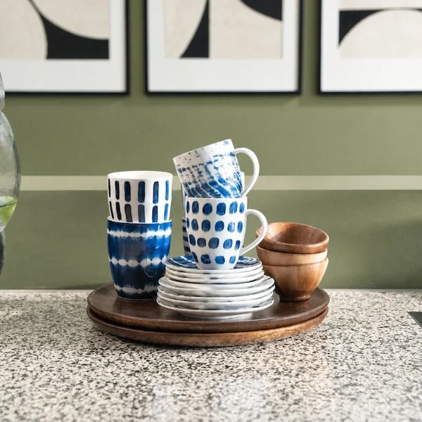 Stacked blue and white ceramic cups and plates on a wooden tray.