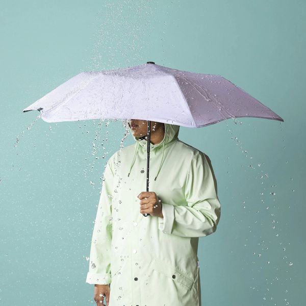 Person holding an umbrella with water pouring off it.