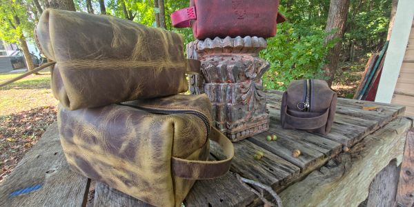 Two leather toiletry bags on a rustic wooden table.