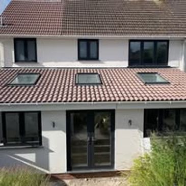 Modern house with tiled roof, skylights, and large black-framed windows.