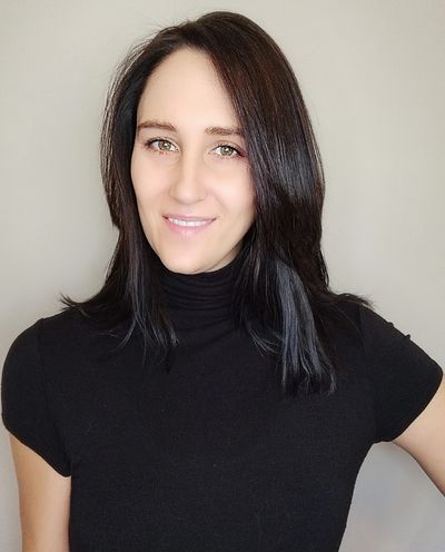 Smiling woman with dark hair wearing a black turtleneck top.