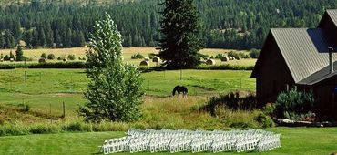 Wedding setup with white chairs on lawn at Stillwater Ranch.