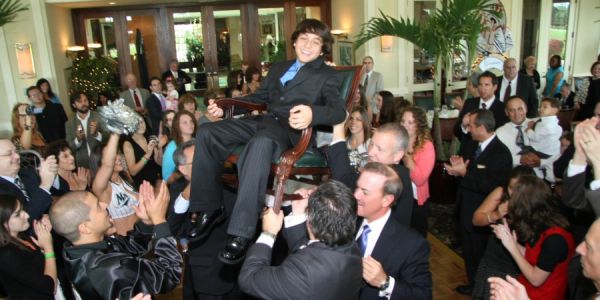 A young man is lifted on a chair during a festive celebration.