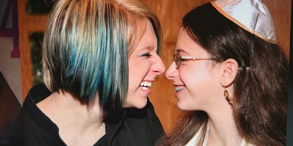 Two girls smiling closely, sharing a joyful moment.
