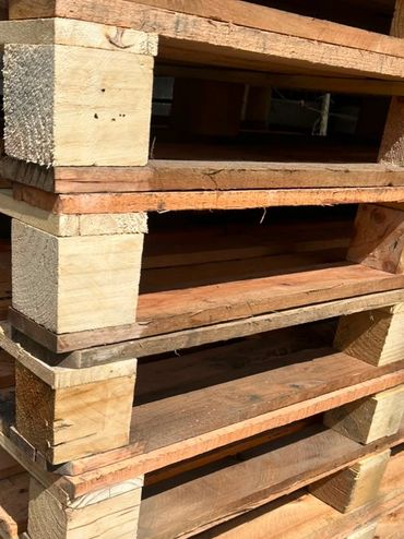 Pilas de tarimas de madera apiladas al aire libre.