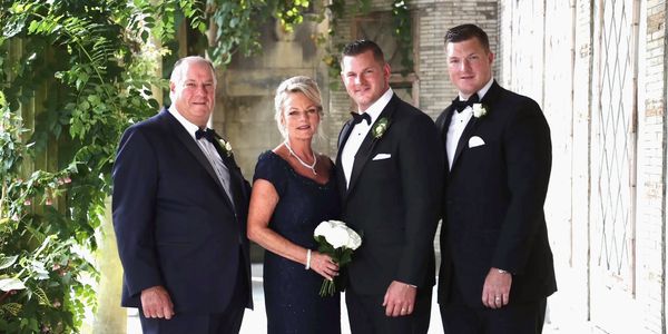 A formal family portrait with four people dressed in elegant attire.
