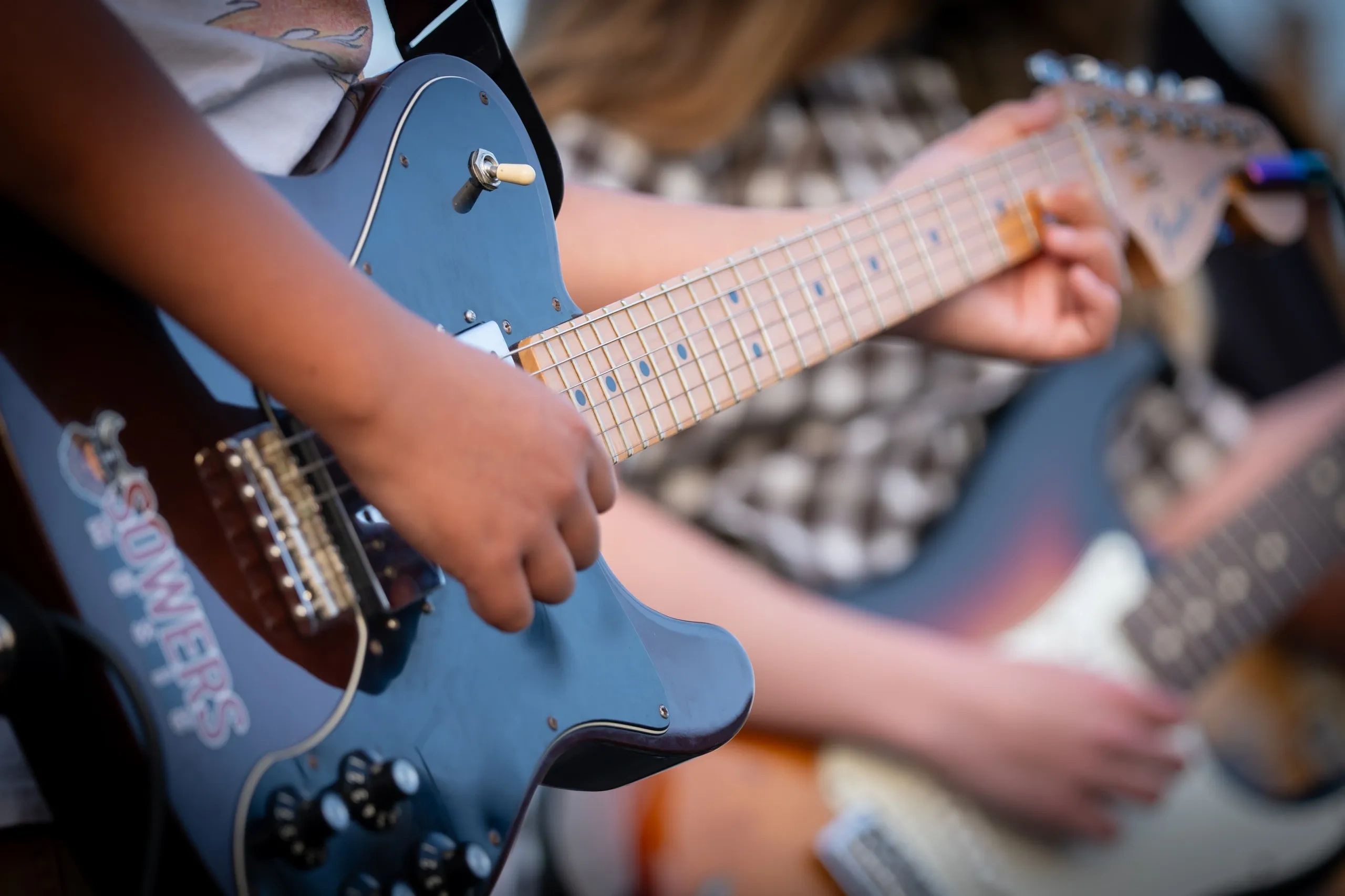 Close-up of two people playing electric guitars together.