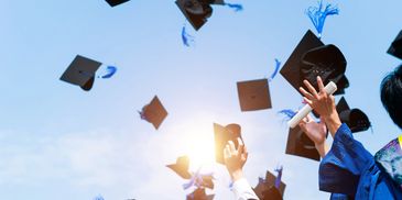 Graduates toss caps into the air celebrating their achievement.