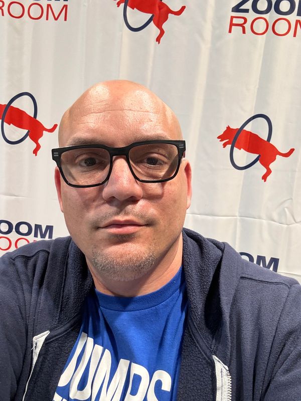 Man with glasses wearing a blue shirt and hoodie.