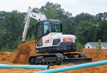 Bobcat excavator digging and moving dirt at a construction site.
