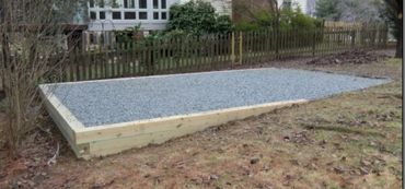 A rectangular gravel bed framed by wooden planks in a backyard.