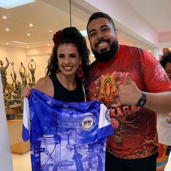 Smiling woman and man posing with a blue and white sports jersey indoors.