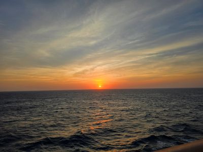 Sunset over the ocean with scattered clouds.