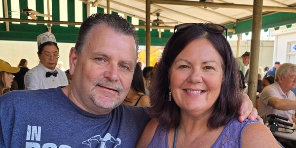 Smiling couple posing together in an outdoor dining area.