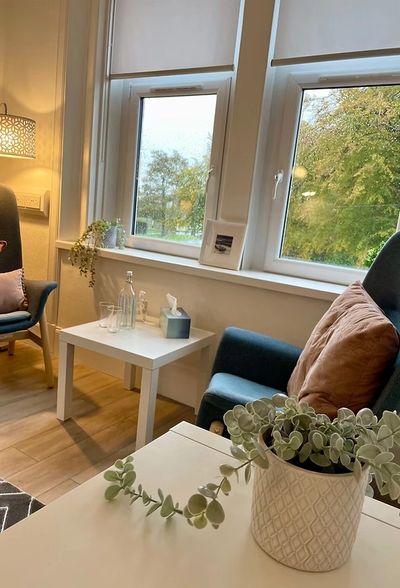Cozy sitting area with armchairs, a plant, and a window view of trees.