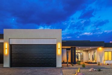 Modern house with a pavered driveway and desert landscaping at dusk.